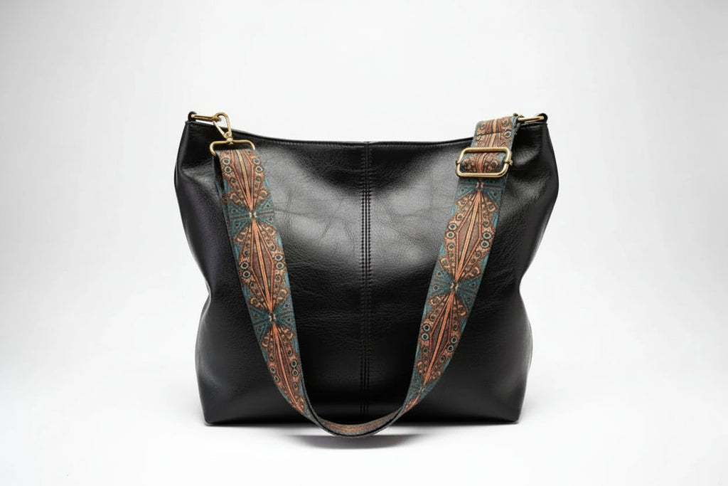 Black leather handbag with decorative brown straps on a white background